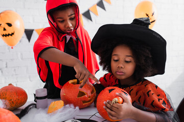 Fototapeta premium Friends embracing the joy of Halloween while crafting pumpkins together
