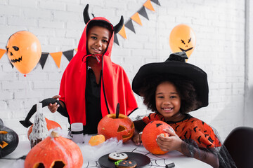 Fototapeta premium Siblings dressed in vibrant Halloween costumes celebrate together with spooky fun