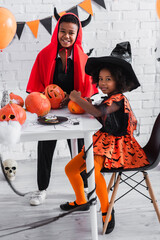 Fototapeta premium Festive siblings joyfully celebrating Halloween in vibrant costumes