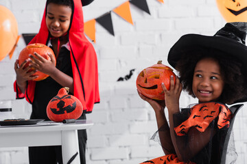 Fototapeta premium Little siblings embrace joy in colorful Halloween costumes during a festive celebration