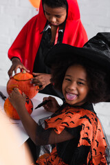 Fototapeta premium Costumed siblings joyfully carving pumpkins during Halloween festivities