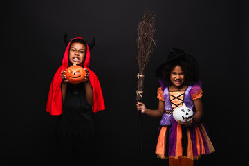 Fototapeta premium Adorable siblings in colorful Halloween costumes ready for trick or treating fun