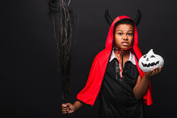 Fototapeta premium Cute little boy celebrating Halloween in a vibrant devil costume with a spooky pumpkin