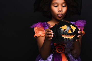 Fototapeta premium Cute little african american girl enjoys halloween with a spooky pumpkin
