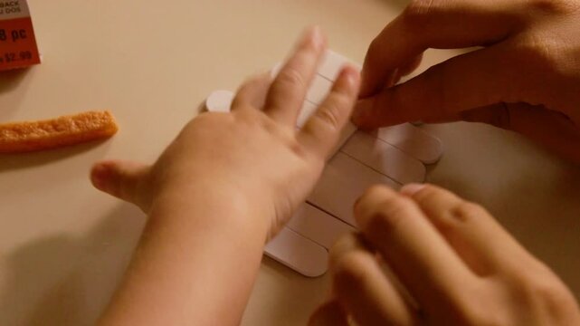Halloween crafts young toddler boy making spooky decorations with mom at living room table in 4K Ultra HD footage.
