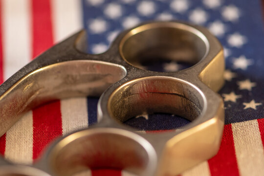 Brass knuckles resting on American flag in dramatic close up