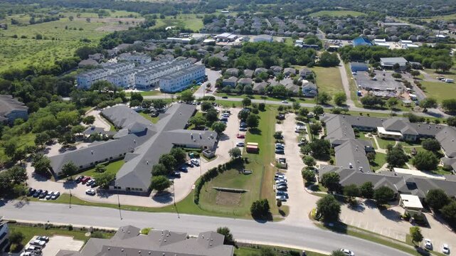 Suburban apartment blocks border Old Lockhart Road near Onion Creek basin. Linear parking lanes, multi story buildings, open green expanses illustrate continuous regional progress, Austin, Texas. USA