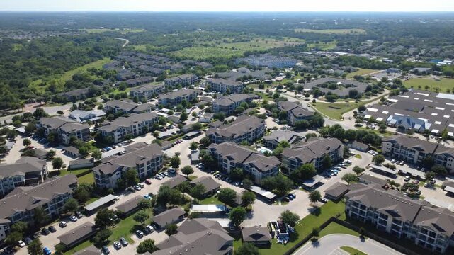 Resort pool courtyards border South I-35 Frontage Road near Slaughter Creek. Modern residential complexes, metal roofs, paved parking lots display vibrant suburban development, Austin, Texas