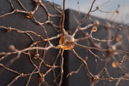 Abstract 3D rendering of a biological neuron with glowing amber core and metallic neural network connections