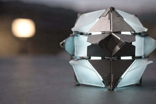 Futuristic geometric glowing cube artifact representing modern technology, artificial intelligence, and innovative sci-fi design on a dark surface