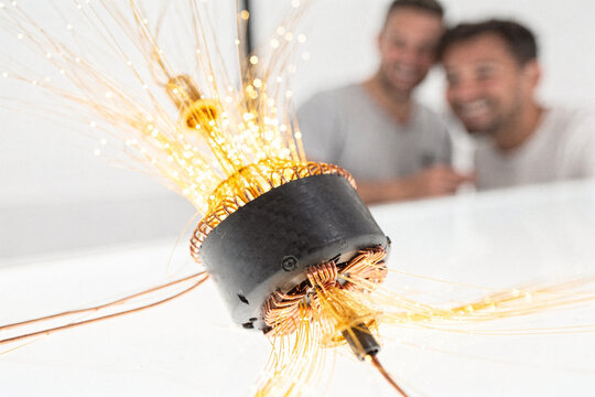 Innovative electric motor prototype with glowing optical fibers and cheerful engineers in laboratory