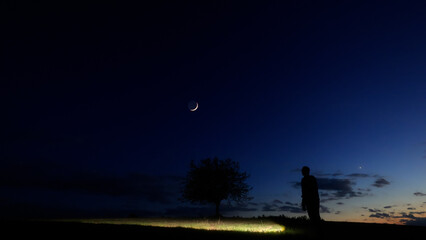Silhouette of a person in nature observing night sky, Moon, stars and planets from a remote location. © astrosystem