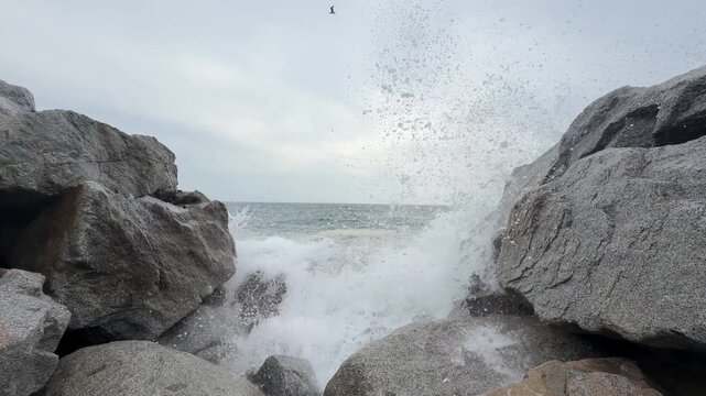 Ola grande rompiendo contra unas rocas de forma violenta