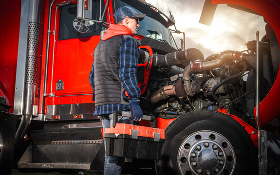Mechanic works on truck engine with toolbox in the late afternoon