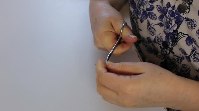 Manicure procedure trim overgrown nails with scissors for hands grooming hygiene routine in 4K Ultra HD footage.
