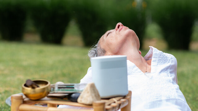 Woman enjoying a peaceful outdoor meditation session with a Schumann wave generator, healing crystals, and sound therapy instruments to encourage relaxation and emotional wellbeing.
