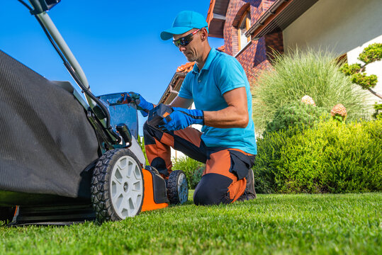 Man mowing a lawn in a residential backyard during daytime