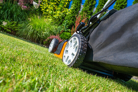 Lawn mower in action on a fresh lawn during bright day