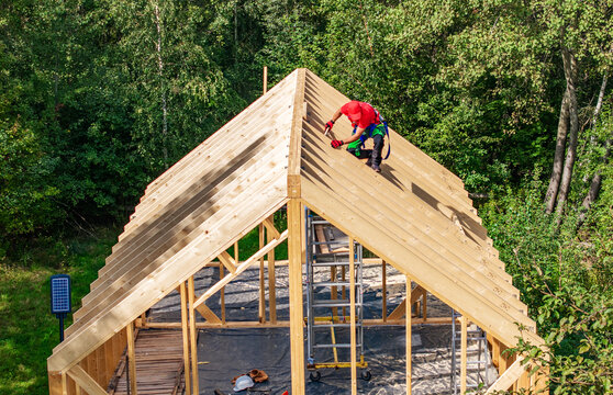 Construction worker installs roof boards on new wooden structure