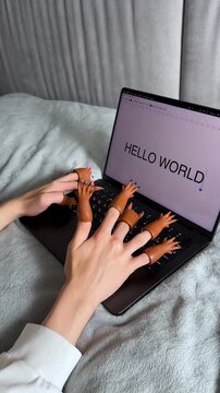 A Quirky Display of Creativity: Miniature Hands Typing 'Hello World!' on a Laptop, Showcasing Whimsical Artistry in a Playful Setting