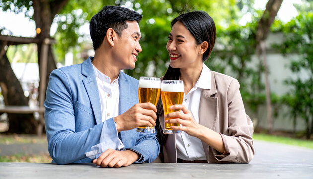 Asian couple celebrating happy moment drinking beer outdoors