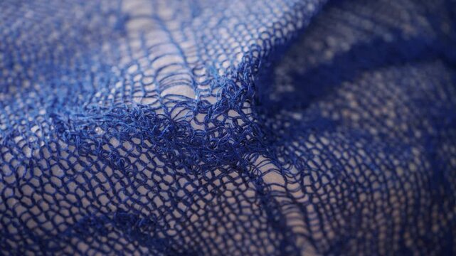 Macro view of blue knitted mesh fabric draped on mannequin in motion.