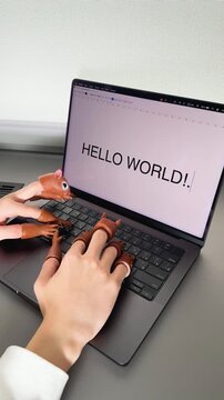 A whimsical scene featuring a pair of hands with playful animal finger puppets typing the words 'HELLO WORLD!' on a laptop, showcasing creativity and fun in digital interaction.