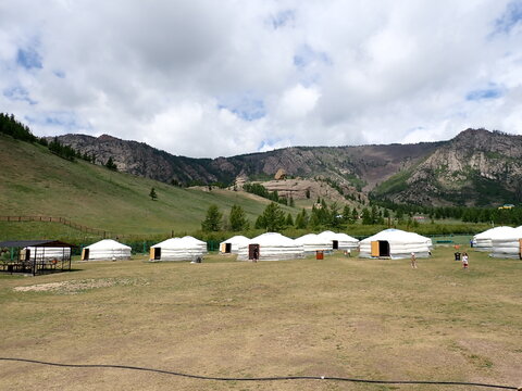 Traditional white Mongolian gers surrounded by rocky mountains and green grassland in Terelj National Park, Mongolia, showcasing the landscape and nomadic culture of Central Asia.