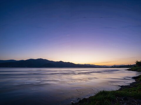 Serene lakeside at dusk with distant mountains