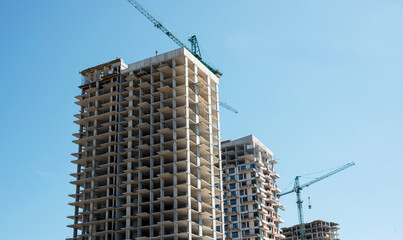 Modern residential buildings under construction with tower cranes and blue sky with white clouds © gorvik