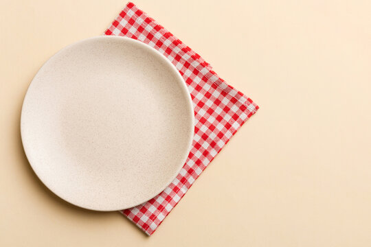 Top view on colored background empty round white plate on tablecloth for food. Empty dish on napkin with space for your design