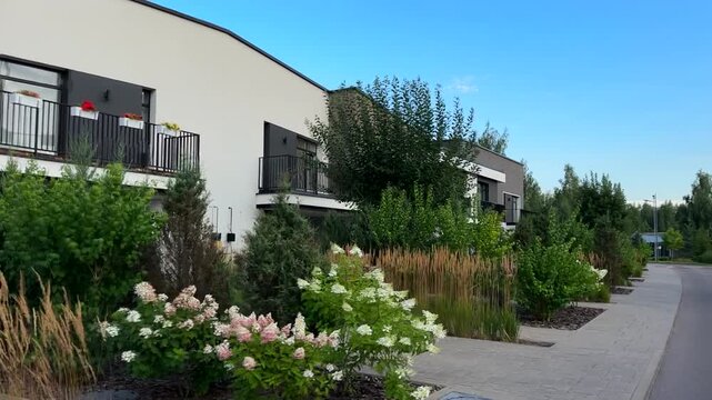 Lush landscaping at townhouse. Residential neighborhood with gardens, greenery at pathways at houses. Stylish buildings, townhouse, duplex apartments in town. Landscape design at modern townhouse. 