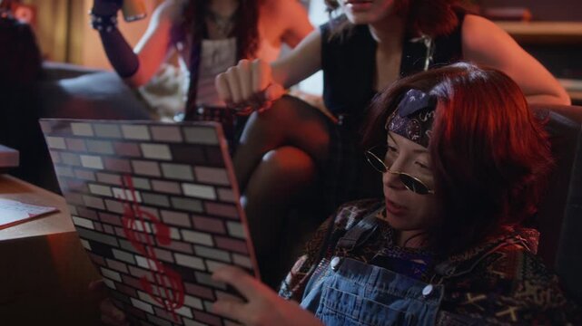 Caucasian young adult woman wearing bandana and sunglasses holding vinyl record sleeve while talking with friends. Video is perfect for music marketing and youth culture advertisements