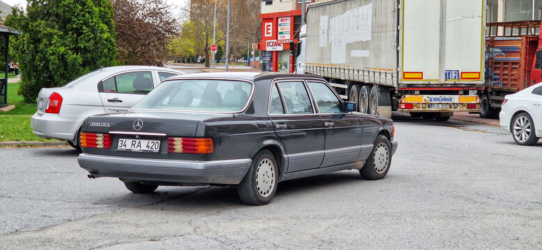 A black Mercedes-Benz 300 SEL W126 S-Class classic car from the 1980s is parked on the side of the road in the city of Konya; a classic German luxury sedan in everyday traffic, Turkey 03.04.25