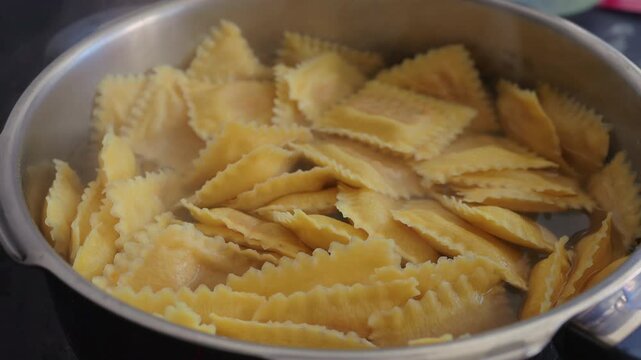 Ravioli pasta boiling in pot on stove, traditional Italian cooking process with homemade cuisine and comfort food concept
