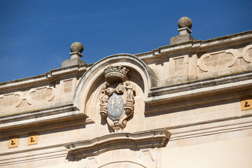 Modica, Italy  1st August 2026: Baroque architectural detail with carved grotesque face and ornate stonework on a balcony in Sicily. © Leckerstudio