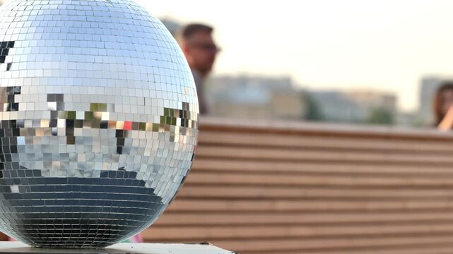 Disco ball reflecting urban city buildings during an outdoor rooftop party