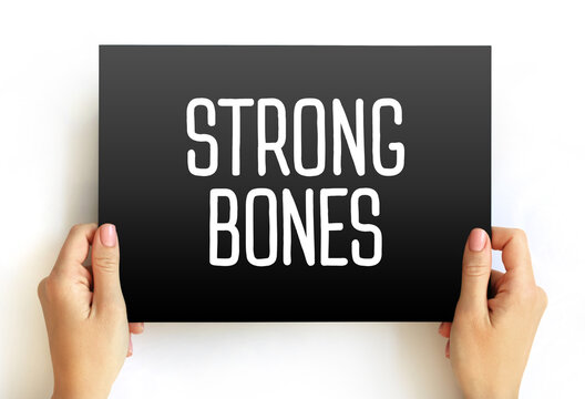 STRONG BONES text on sign held by hands. Concept for physical strength, calcium sufficiency, and skeletal durability. Image captures orthopedic health and fitness goals for a resilient body.