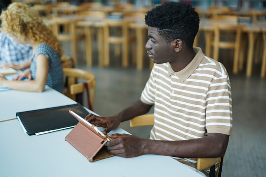 Young african boy student using digital tablet inside univerity library - Back to school, multiracial people and study concept