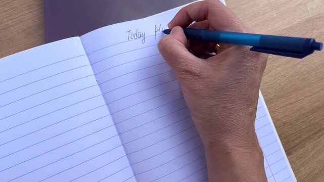 Hand holding pen and writing on lined paper, workflow management, smart planning.