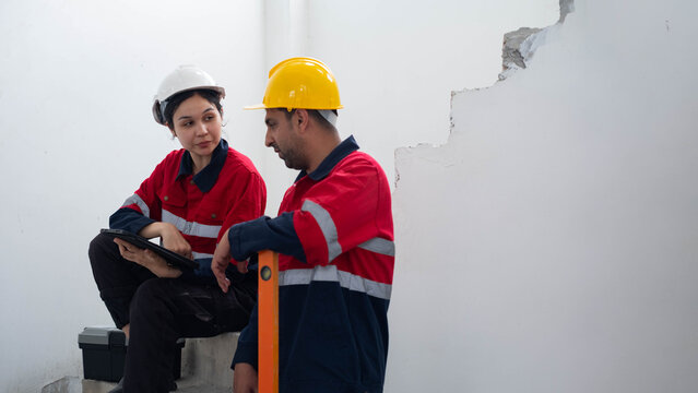 Construction engineers reviewing a building inspection on unfinished concrete stairs using a digital tablet and leveling tool. Professional teamwork, workplace safety, renovation, site management.