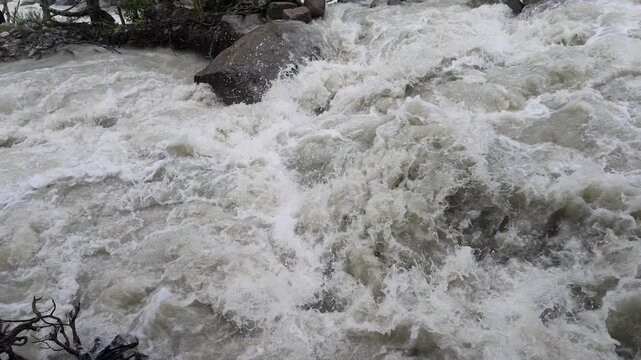 Powerful rapid glacial river with muddy white water cascading over rocks at Shkhara glacier in Svaneti region Georgia, fast flowing mountain stream, wild nature energy