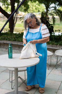 Senior woman searching bag at outdoor cafe table