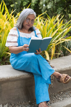 Senior woman reading book in park enjoying leisure time