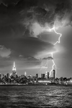 Lightning striking over the Midtown Manhattan skyline during a nighttime thunderstorm viewed across the Hudson River, New York City, USA (Black and White)