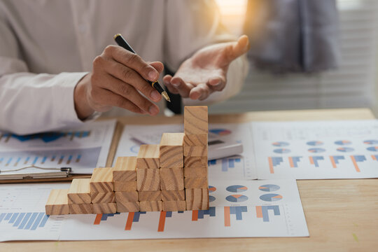 Businessman Using Calculator to Calculate Financial Growth, Investment Strategy and Mortgage Planning with Wooden Block House Stairs