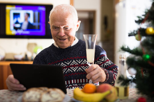 Cheerful senior man making video call on tablet at Christmas