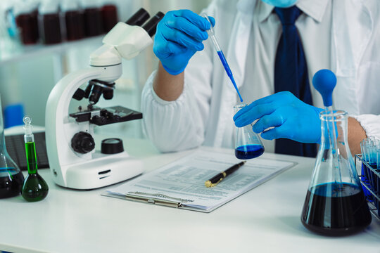 Scientist Using Pipette to Transfer Liquid Solution in Glass Flask with Test Tubes in Laboratory Research