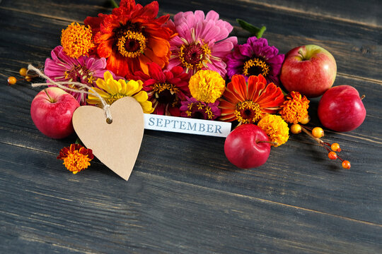 September calendar. calendar block with September month, paper heart shape blank card, colorful flowers and red apples close up on brown wooden table background. Back to school, Knowledge Day.