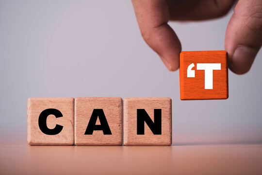 Hand changes wooden blocks from CAN'T to CAN symbolizing positive mindset, motivation, confidence, self belief, overcoming limitations, personal growth and achieving success through determination.